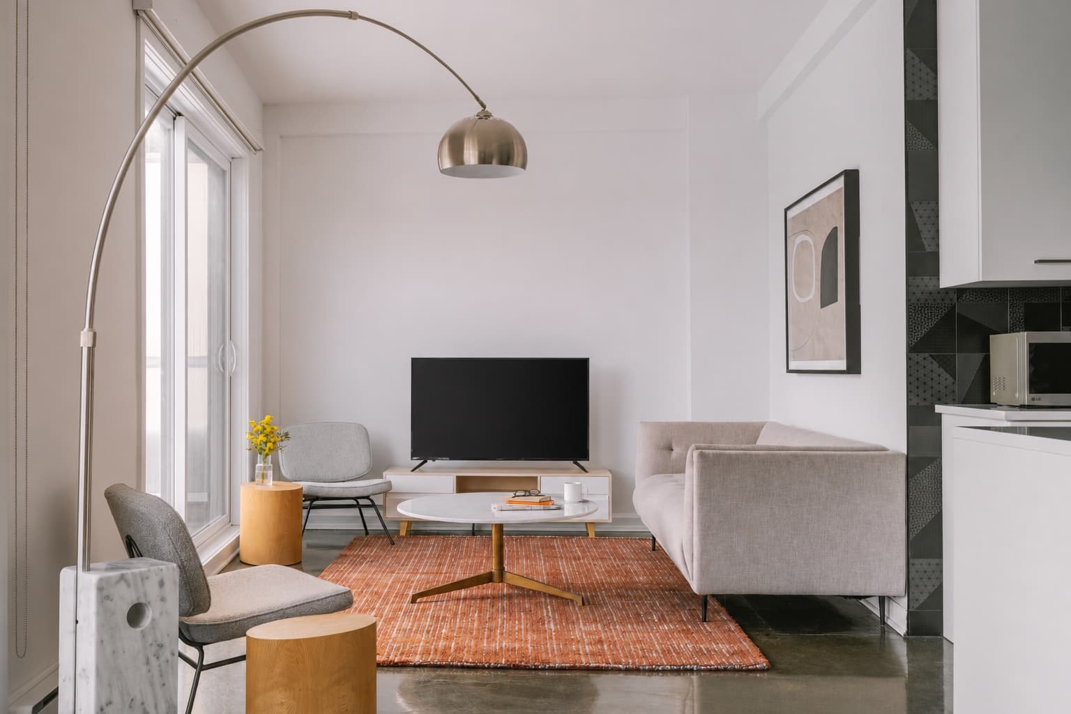 Scandinavian living room with a light sofa, orange rug, and daylight from a tall window